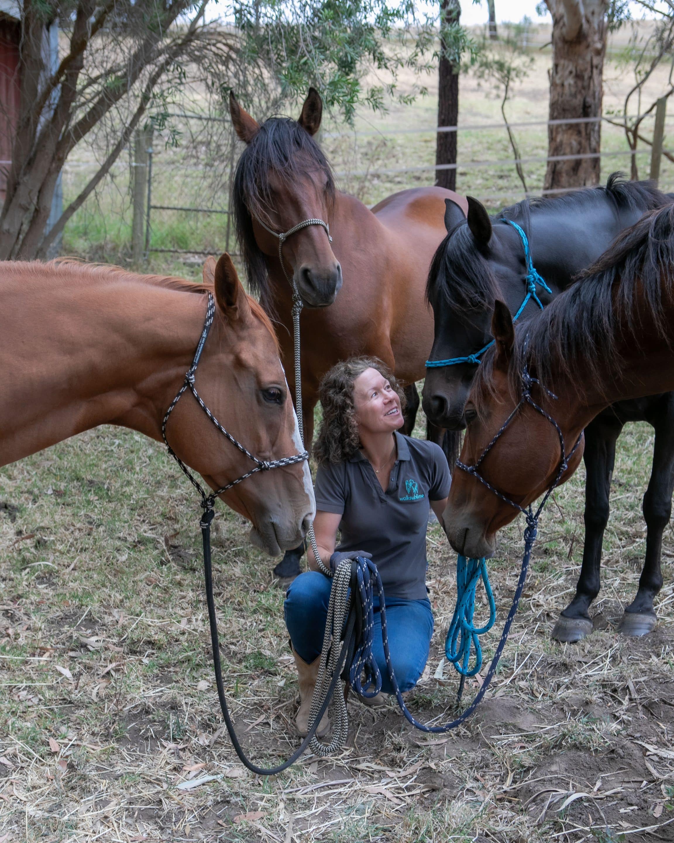 Woman kneeling down in the centre of a circle of horses