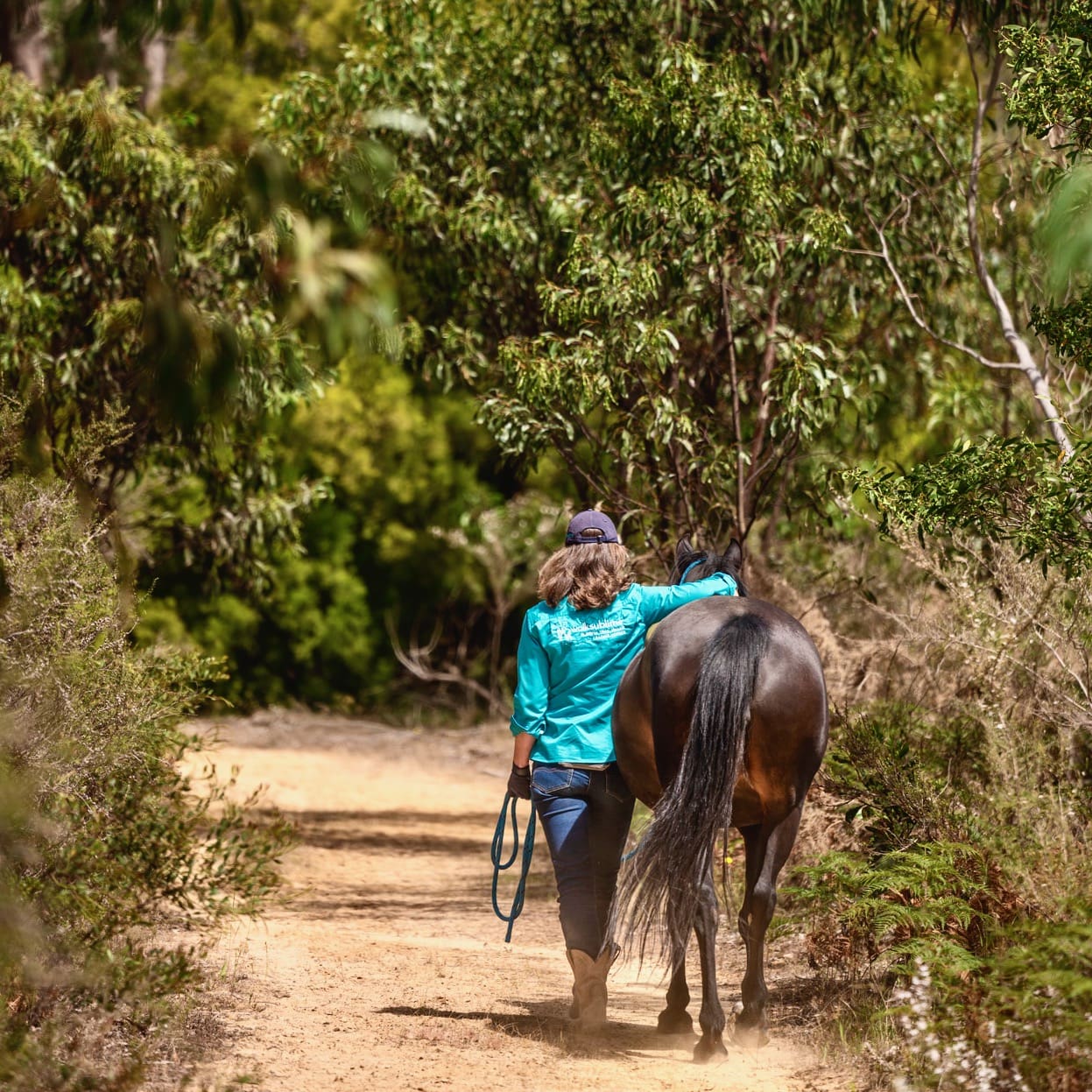 Lady trail walking next to her horse with her arm over the horse's neck